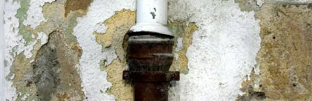 Leaking pipe with water-stained, peeling wall plaster