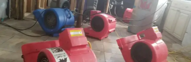 Red air movers drying a water-damaged room