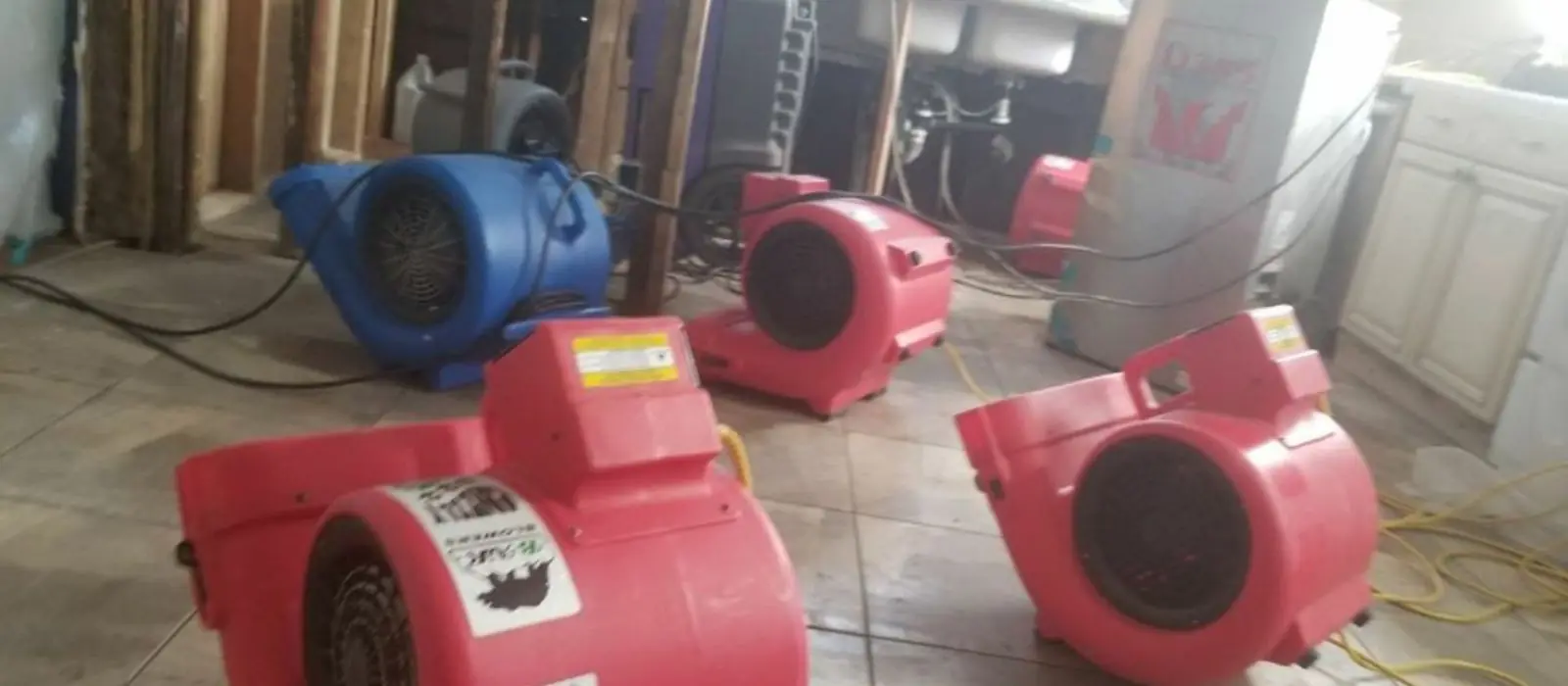 Red air movers drying a water-damaged room