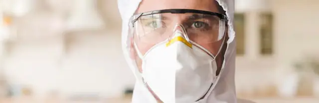 Person in a respirator mask and protective hood