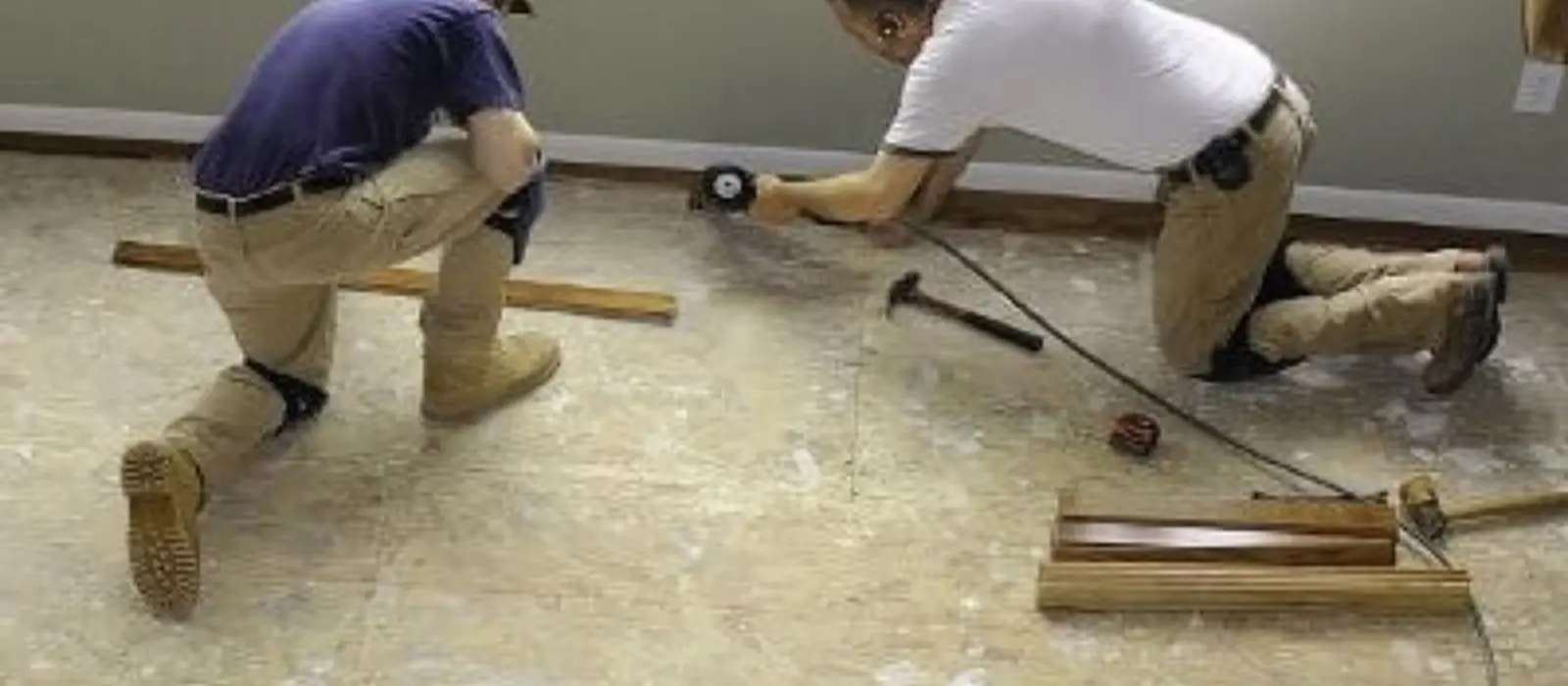 Two workers repairing a floor after water damage